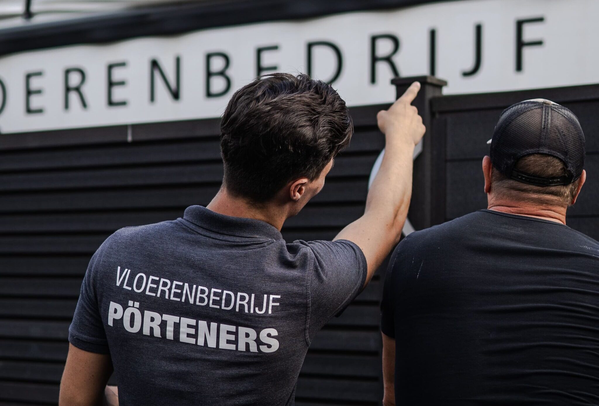 Werknemer van Portener wijst naar de werkbus waar de cementdekvloer in zit